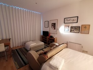 Ein Hotelzimmer mit Bett, Schreibtisch, Stuhl, einer Couch und einem Heizkörper.