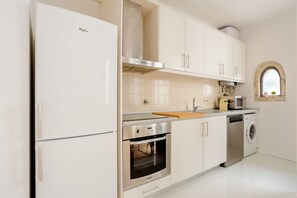 Eine Küche mit Kühlschrank, Backofen, Geschirrspüler und einem Fenster mit Blick.