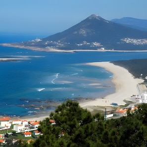 Un pueblo costero con una playa, una montaña al fondo y edificios residenciales.