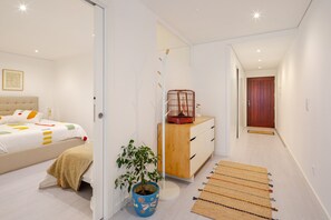 Un dormitorio moderno con una cama, mesita de noche y una planta en maceta.