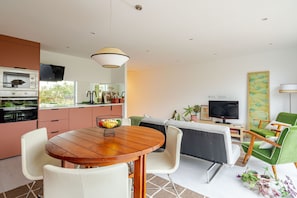 Una cocina moderna con horno empotrado y comedor con mesa y sillas de madera.