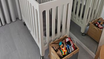Ein weißes Babybett mit einer Aufbewahrungsbox und einem Spiegel.