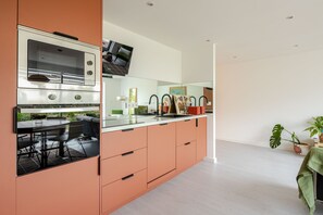 Una cocina moderna con horno empotrado y comedor con mesa y sillas.