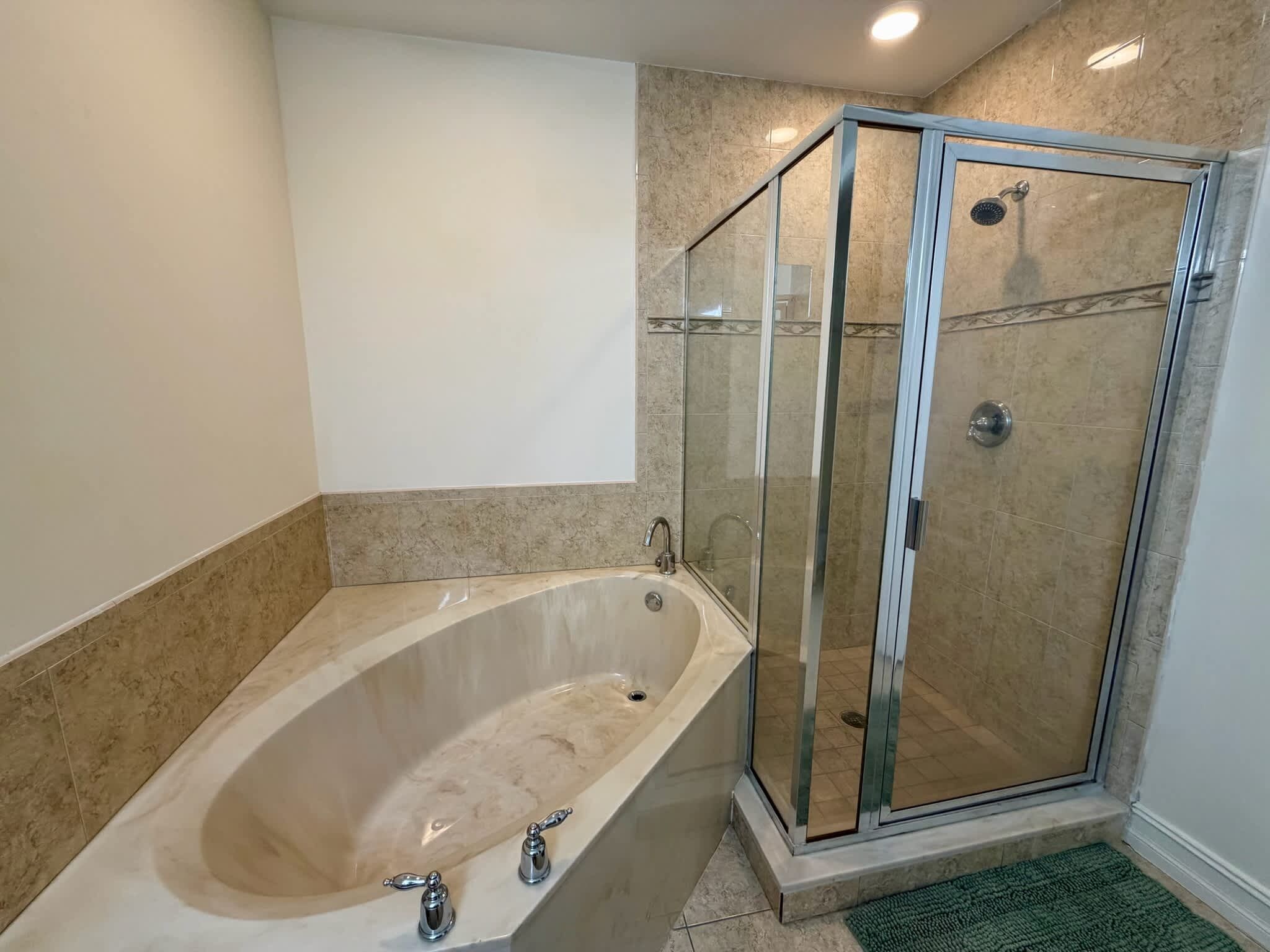 Ein Badezimmer mit einer freistehenden Badewanne, einer Duschkabine und einer grünen Fußmatte.