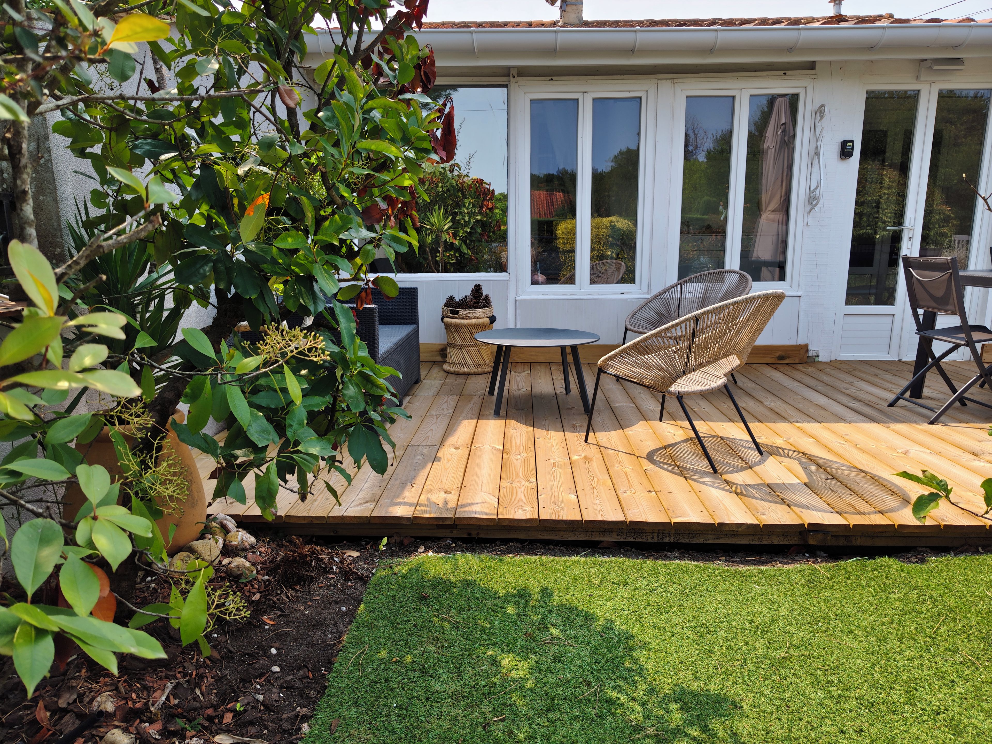 A wooden deck with outdoor furniture, a small table, and chairs.