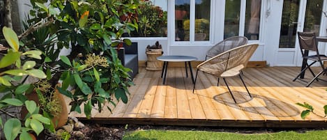 A wooden deck with outdoor furniture, a small table, and chairs.