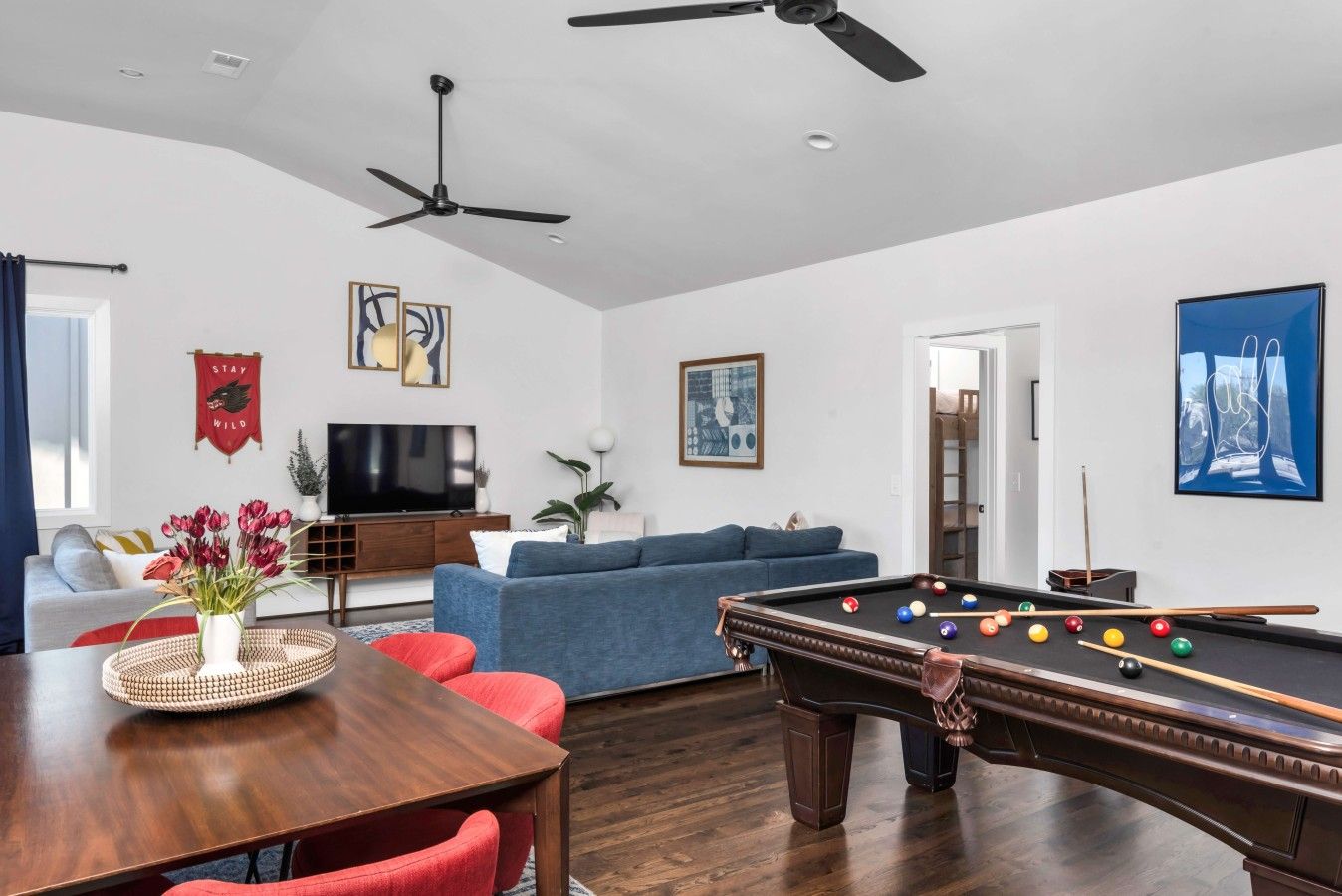 A living room with a pool table, a sofa, a television, and a ceiling fan.