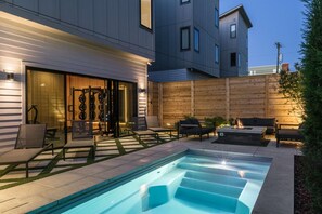 A modern outdoor pool area with a built-in hot tub, lounge chairs, and a wooden fence. - Sunny Modern Oasis • Pool, Hot Tub, Fire Pit, Grill, Rooftop (Nashville)