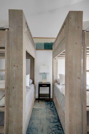 A room with two bunk beds, a bedside table with a lamp, and a blue carpet. - Sunny Modern Oasis • Pool, Hot Tub, Fire Pit, Grill, Rooftop (Nashville)