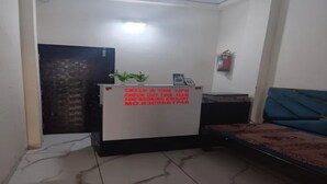 Un mostrador de recepción con un cartel que indica los horarios de registro de entrada y salida, un teléfono y una pequeña planta.