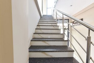 Una escalera con escalones de mármol y barandillas de metal, que asciende.