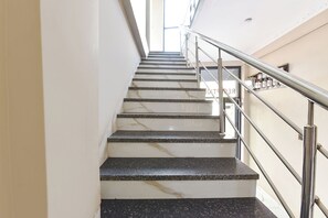 Una escalera con escalones de mármol y barandillas de metal, que asciende.