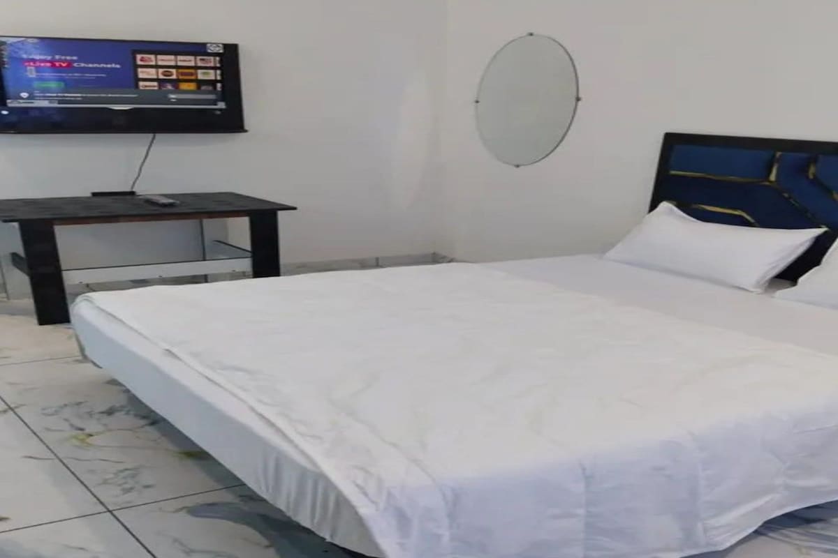 Una habitación de hotel con cama, televisión, escritorio y espejo fijado a la pared.