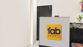 A reception desk with a sign for 'fab HOTELS' and a potted plant on the right.