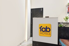 Una taulell de recepció amb un cartell de 'fab HOTELS' i una planta en maceta a la dreta.