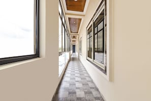 Un pasillo con amplias ventanas a ambos lados, que conduce a una puerta al final.