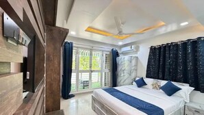 A modern bedroom with a large bed, a ceiling fan, and a view of the outdoors. - Fabhotel Balewadi Stay Inn (Pune)