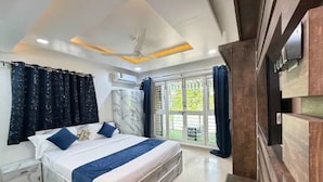 A bedroom with a bed, curtains, a ceiling fan, and a view of the outdoors. - Fabhotel Balewadi Stay Inn (Pune)