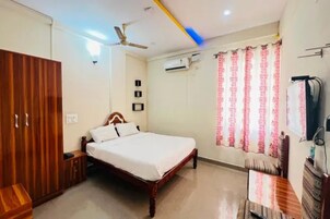 Un dormitorio con cama, armario, ventilador de techo, aire acondicionado y cortinas.