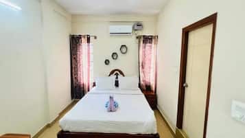 A bedroom with a bed, a door, an air conditioning unit, and a window with curtains.