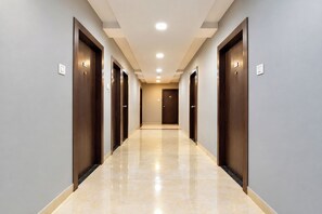 A hotel corridor with multiple doors, a tiled floor, and recessed ceiling lighting. - FabHotel D9 (Indore)