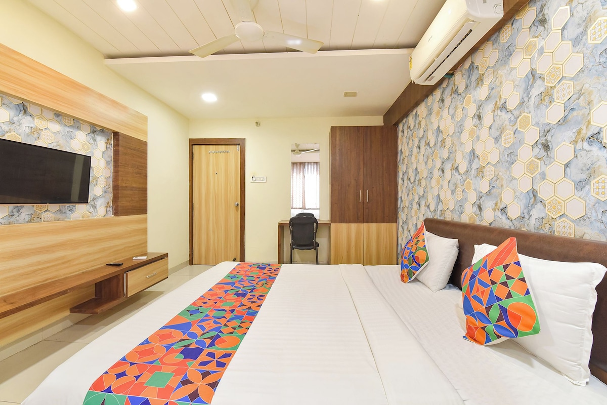 A hotel room with a bed, a desk, a chair, a TV, and a wardrobe.