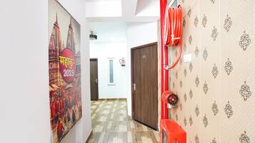 A corridor with patterned wallpaper, a red fire hose, and a door marked with the number 102.