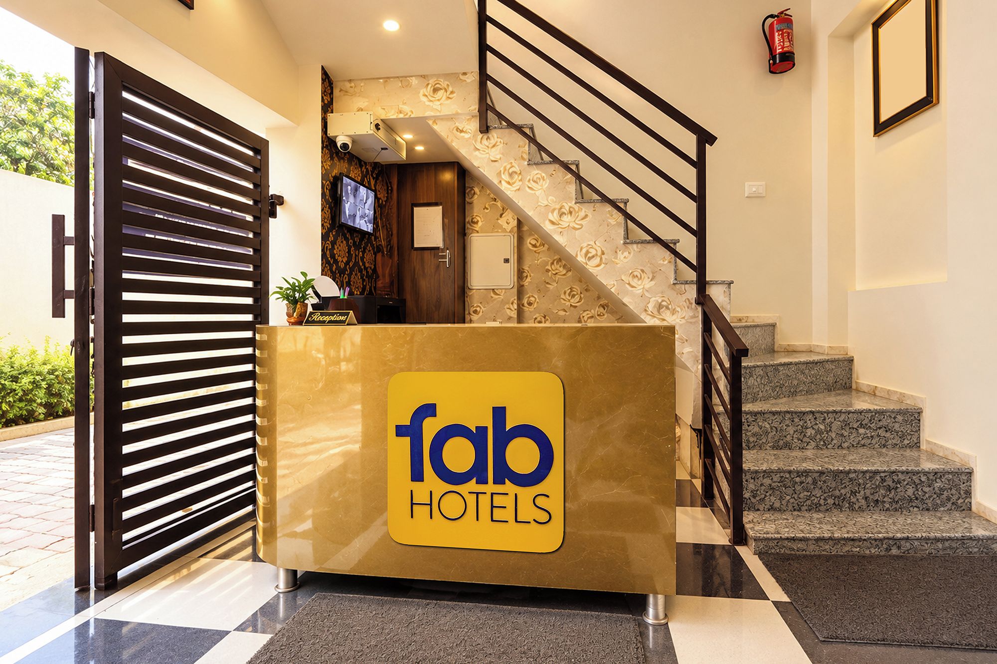 Eine Rezeption mit einem ‚fab hotels‘ Schild, eine Treppe mit Geländer und ein an der Wand befestigter Feuerlöscher.