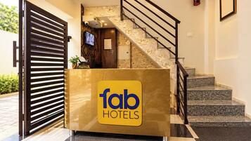 Eine Rezeption mit einem ‚fab hotels‘ Schild, eine Treppe mit Geländer und ein an der Wand befestigter Feuerlöscher.