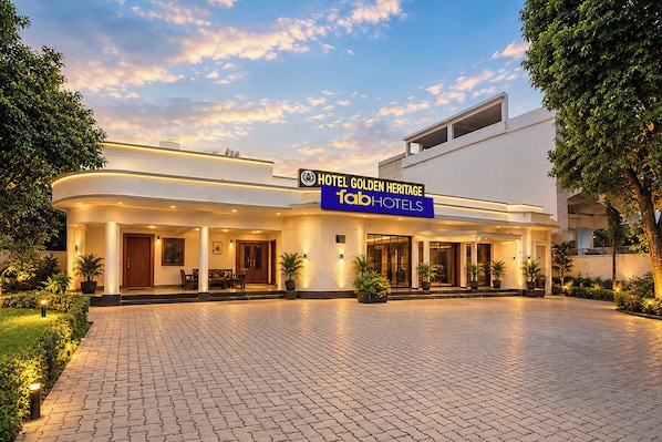 A hotel with a modern facade, a signboard, and a paved entrance area.