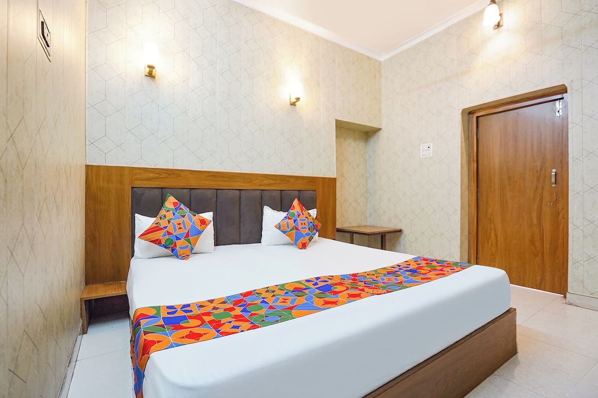 A hotel room with a bed, a wooden headboard, a nightstand, and a door.