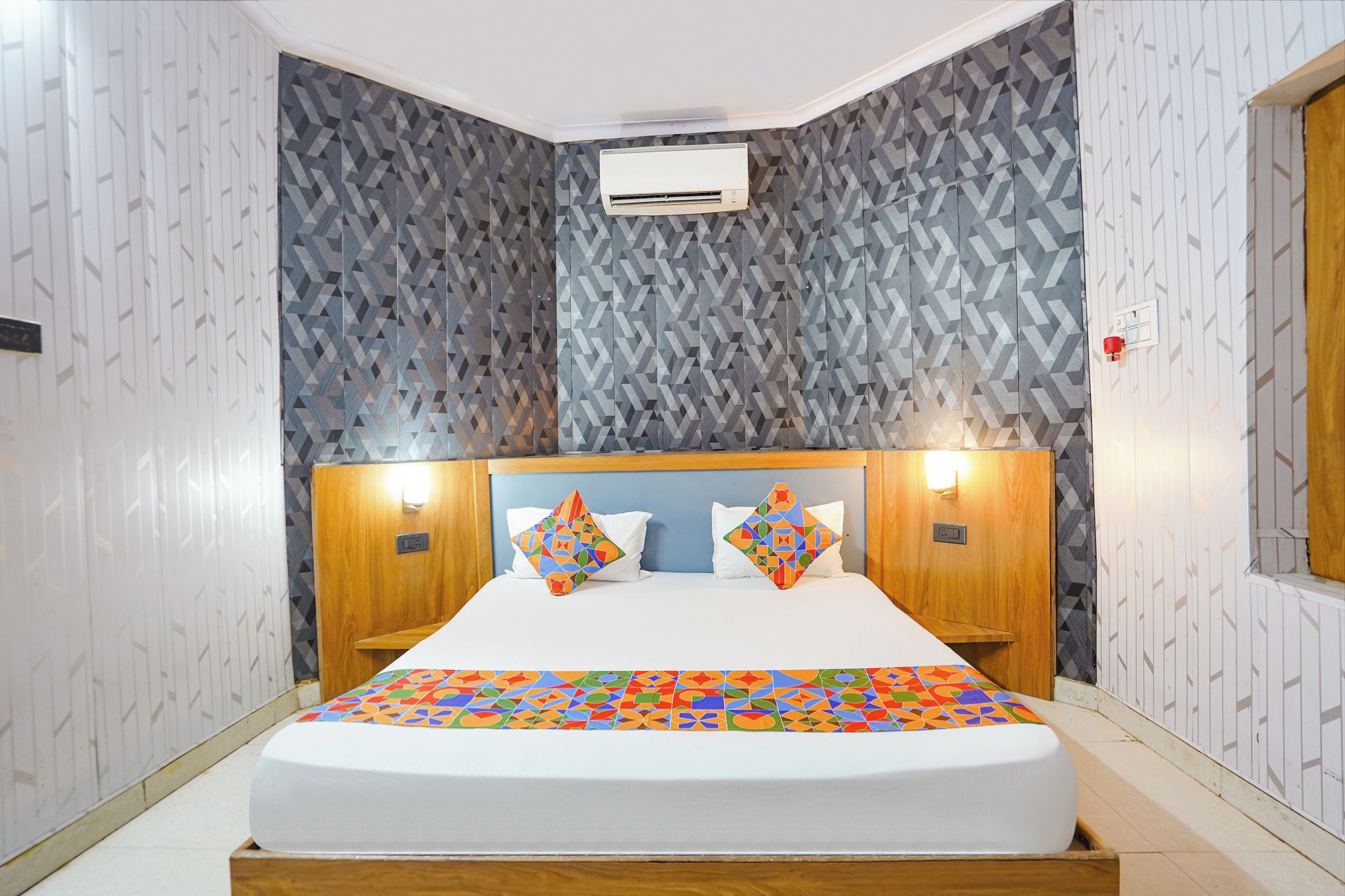 A hotel room with a large bed, a wooden headboard, and patterned wallpaper.