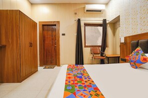 Habitación de hotel con cama, armario de madera, ventana con cortinas y aire acondicionado de pared.
