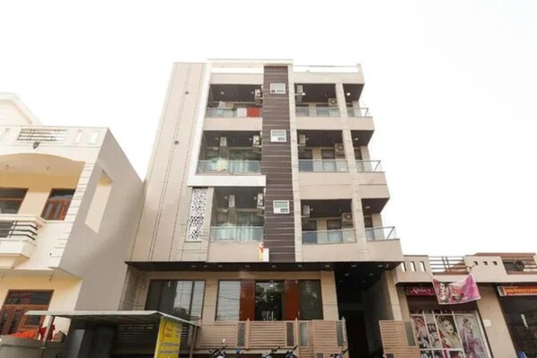 A multi-story building with balconies, large windows, and a central entrance.