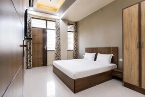 A bedroom with a large bed, a wardrobe, and a window with curtains.