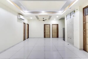 A spacious room with a tiled floor, two wooden doors, and a ceiling fan.