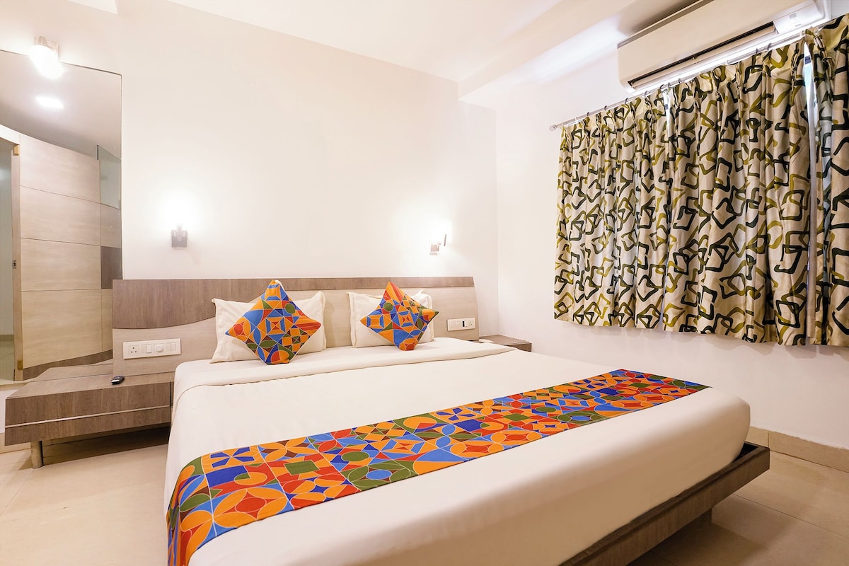 Una habitación de hotel moderna con una cama, una mesita de noche, un espejo y un equipo de aire acondicionado.