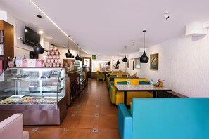 Interior de un restaurante con una barra larga, zona de estar y un expositor.