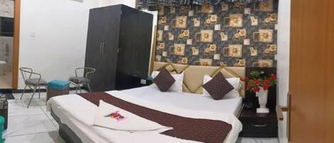 A hotel room with a bed, a wardrobe, a chair, and a wall with patterned wallpaper.