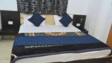Una cama con una colcha estampada, dos almohadas y un cabecero con una cortina estampada arriba.