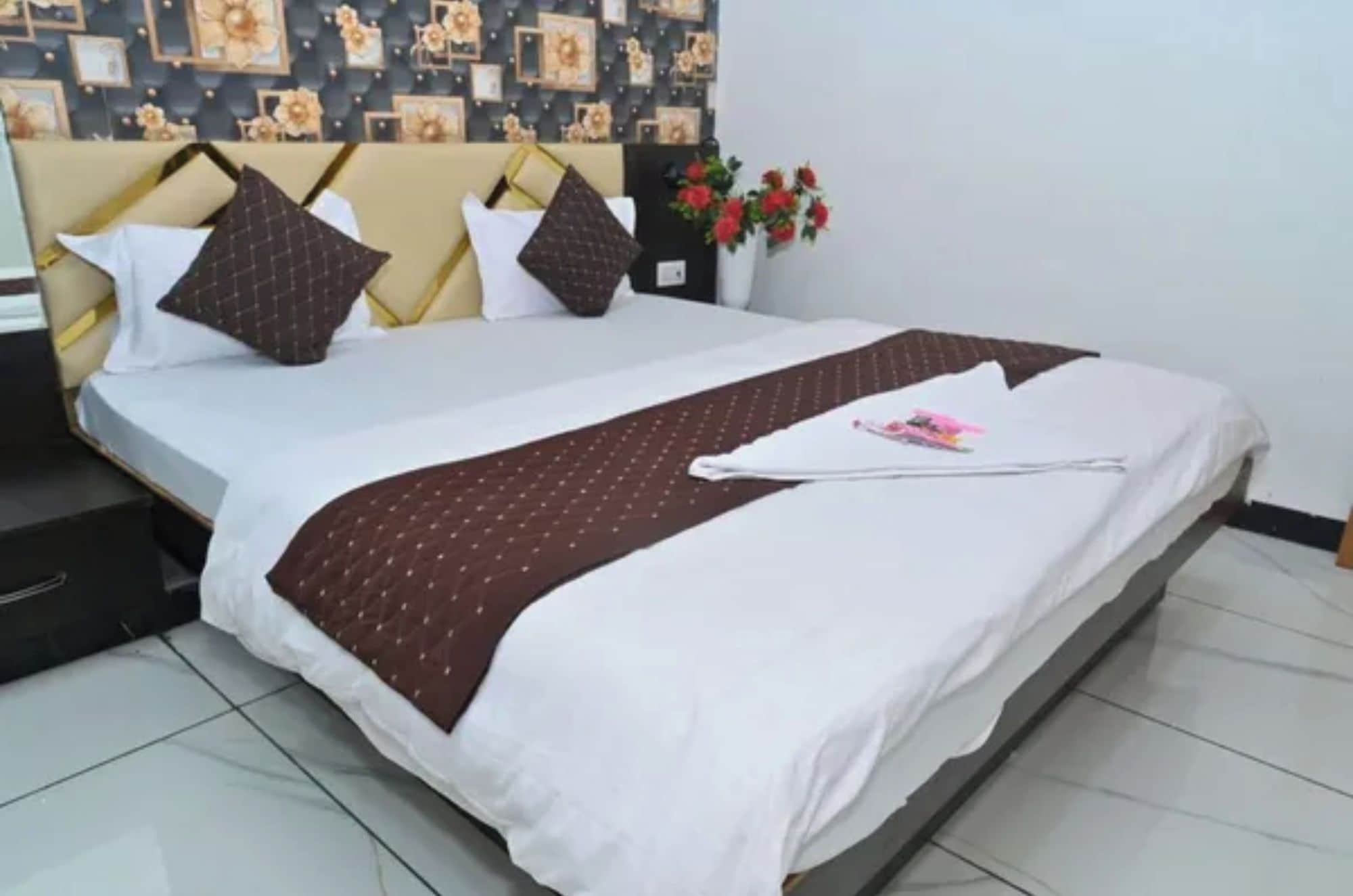 A neatly made bed with a white and brown bedspread, a single pillow, and a decorative pillow on a headboard with a floral pattern.