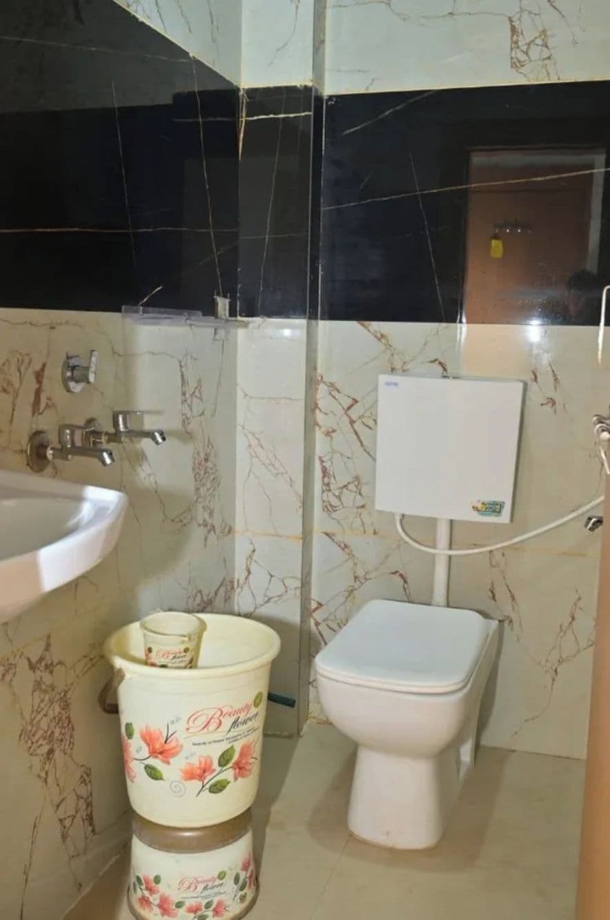 A bathroom with a sink, toilet, and a trash bin.