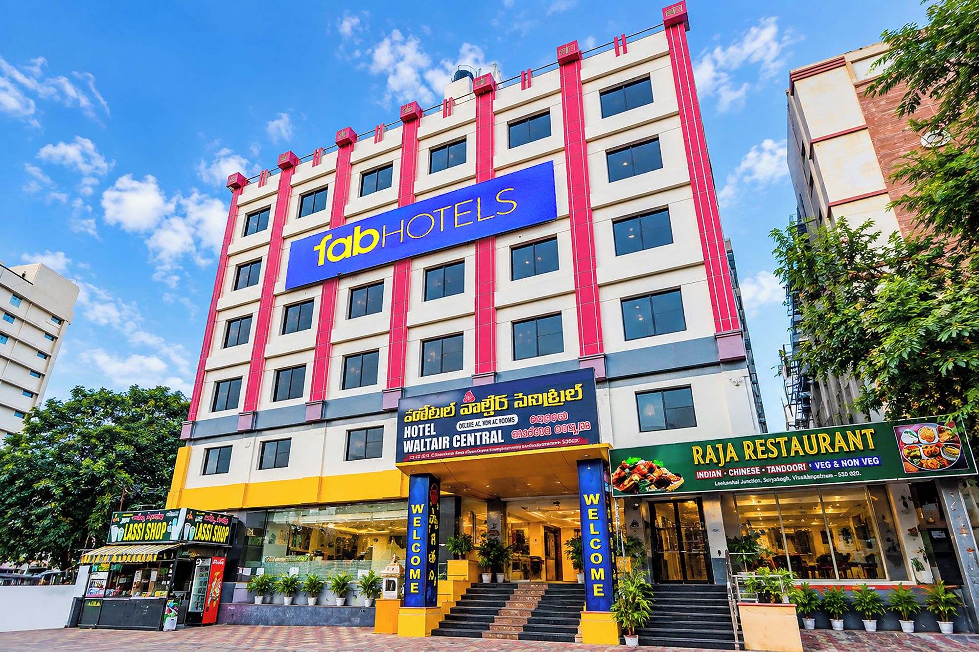 A multi-story hotel with a prominent sign for 'fab hotels' and a 'Rajah Restaurant' offering various cuisines.