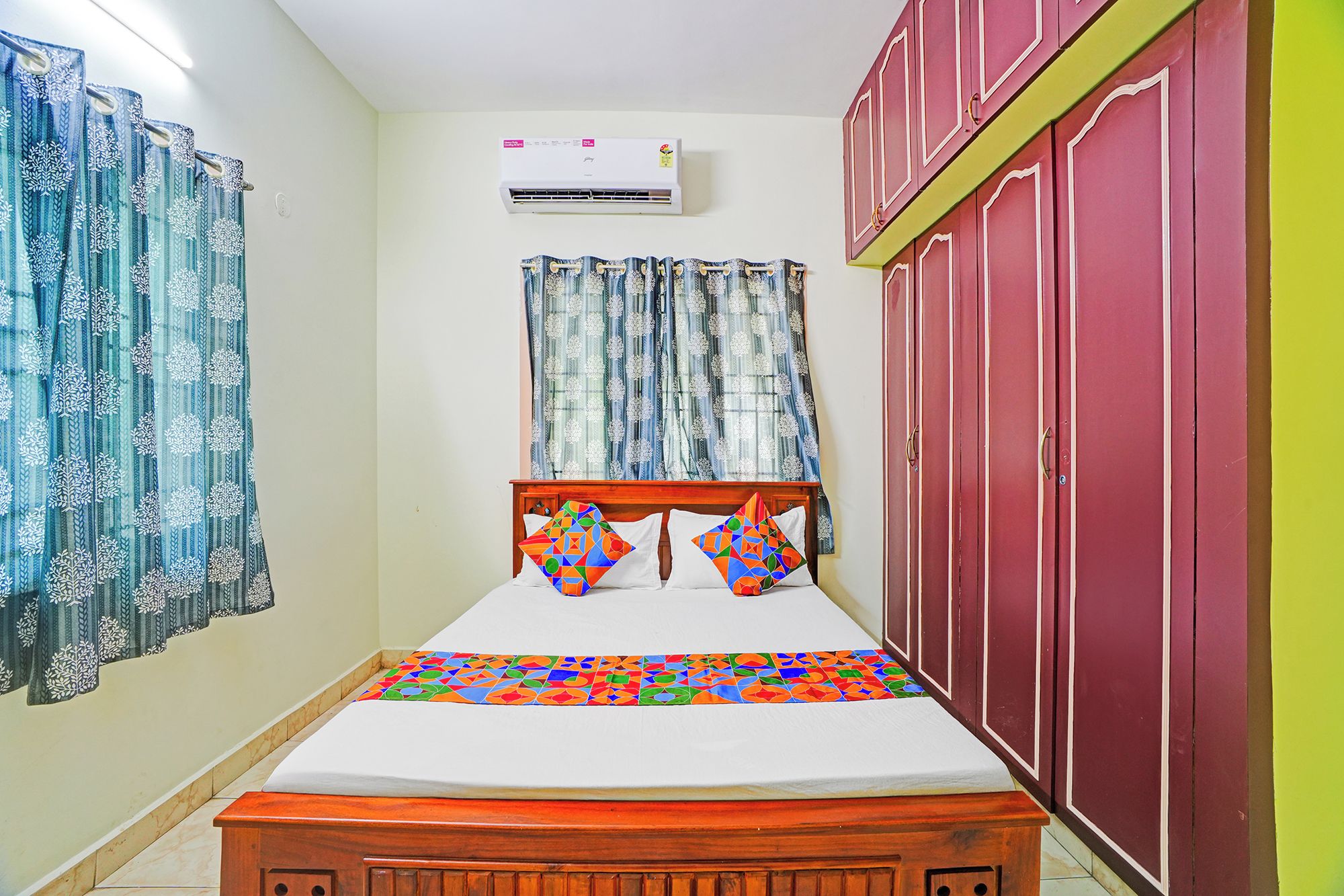 Een slaapkamer met een bed, gordijnen, een airconditioner en een kledingkast.