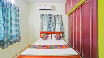 Een slaapkamer met een bed, gordijnen, een airconditioner en een kledingkast.