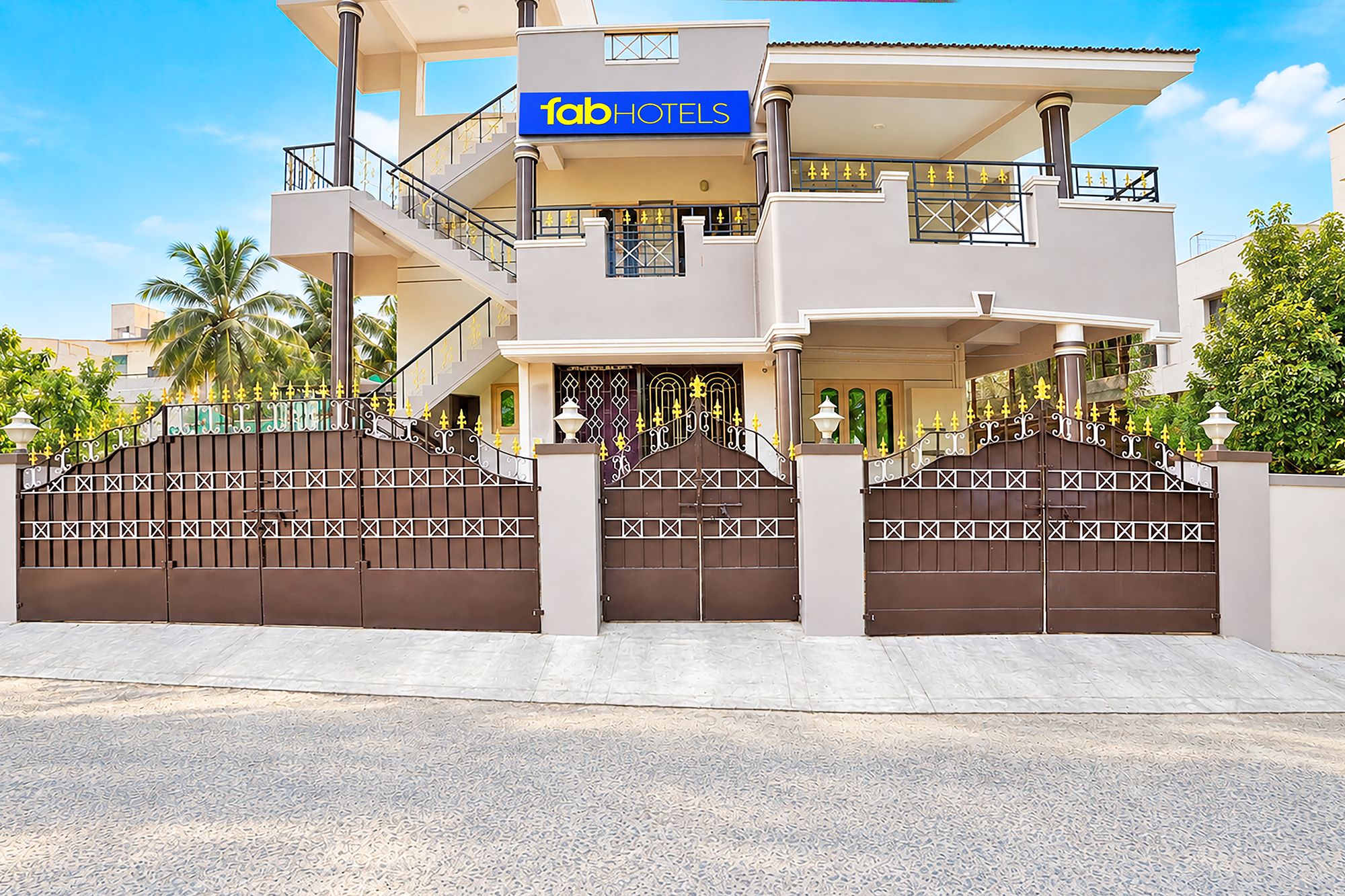 Un hotel moderno con una estructura de dos pisos, una entrada con puerta de rejas y un letrero visible de 'FabHotels'.