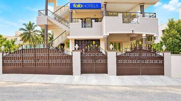 Un hotel moderno con una estructura de dos pisos, una entrada con puerta de rejas y un letrero visible de 'FabHotels'.