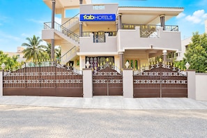 A modern hotel with a two-story structure, a gated entrance, and a visible sign for 'FabHotels'.