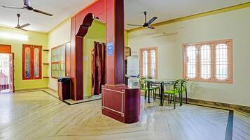 A hotel room with a large mirror, a water dispenser, a table with chairs, and ceiling fans.