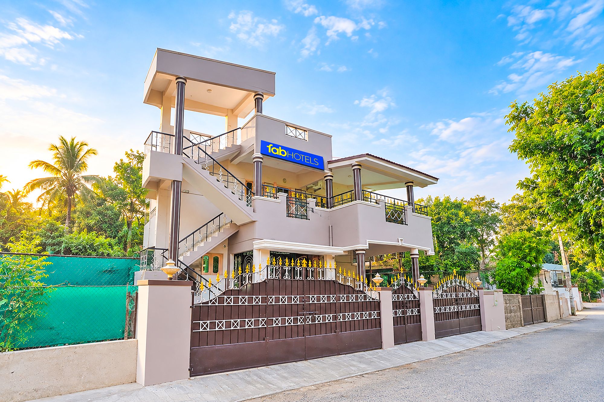 Um hotel moderno com estrutura em dois andares, varanda coberta e entrada com portão.